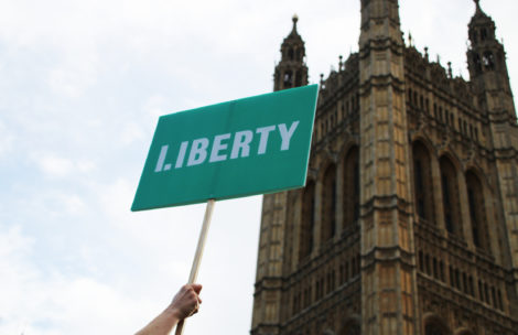 Person holding up Liberty branded placard outside parliament.