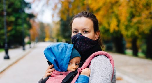Mum wearing face mask carrying baby