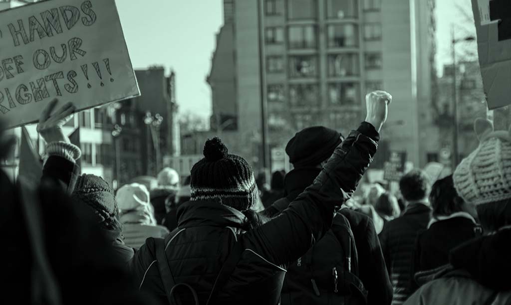 A protester raises their fist in the air at a large demonstration