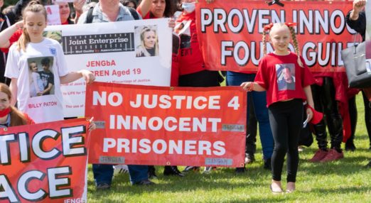 A protest by JENGbA. Young protesters holding banner with 'no justice 4 innocent prisoners' written on it.